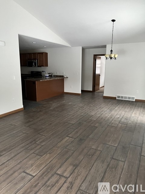 A room with wooden flooring and a kitchen area.