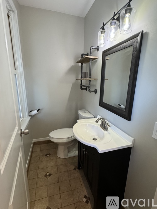 A bathroom with a toilet, sink, and mirror.