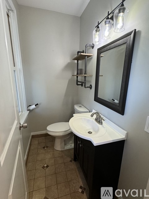 A bathroom with a toilet, sink, and mirror.