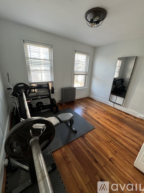 A gym room with a weightlifting bar in the foreground.