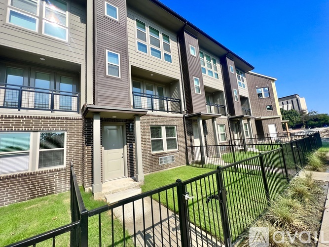 A row of apartment buildings with black fencing in front.