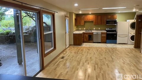A kitchen with wooden floors and a washer and dryer stacked together.