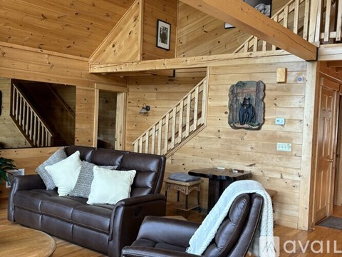 A living room with a brown leather couch and a wooden wall.