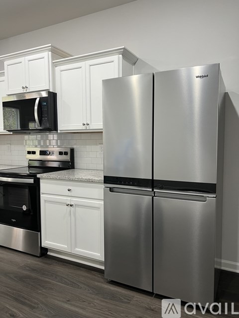 A modern kitchen with a stainless steel refrigerator and white cabinets.