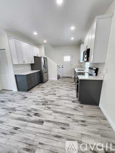 A kitchen with white cabinets and a wooden floor.