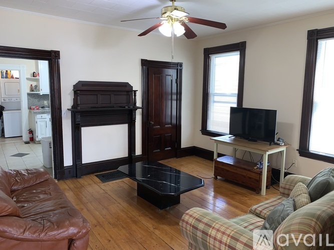 A living room with a brown leather couch and a wooden floor.