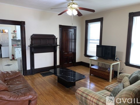 A living room with a brown leather couch and a wooden floor.