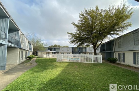 A tree stands in the middle of a grassy area between two apartment buildings.