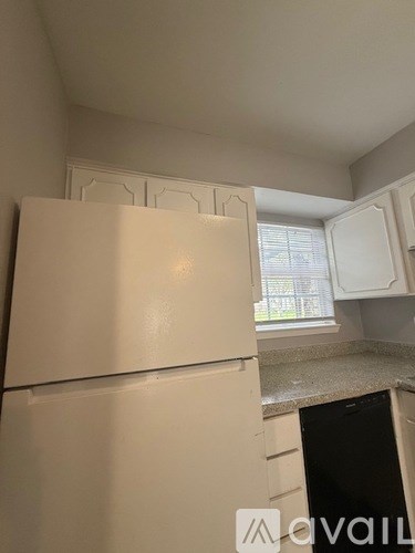 A white refrigerator in a kitchen with a window in the background.