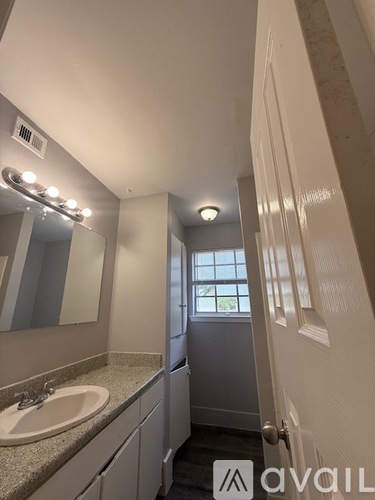 A bathroom with a sink, mirror, and a window.