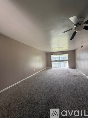 A room with a fan and carpeted floor.