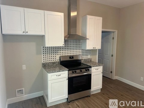 A kitchen with white cabinets and a black and white checkered backsplash.