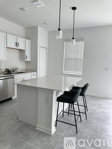 A kitchen with a white island and black chairs.