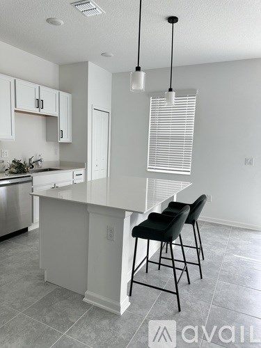 A kitchen with a white island and black chairs.