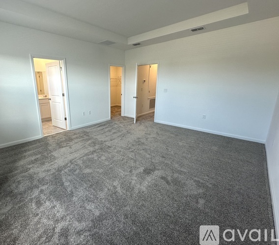 A spacious room with grey carpeting and white walls.