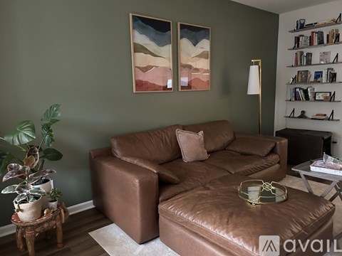 A living room with a brown couch and a painting on the wall.
