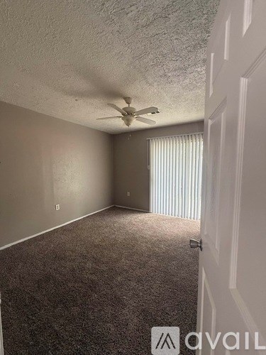A room with a ceiling fan and carpeted floor.