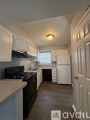 A kitchen with white cabinets and black appliances.
