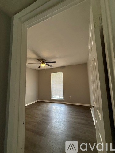 A room with a ceiling fan and wooden flooring.
