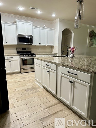 A kitchen with white cabinets and a granite countertop.