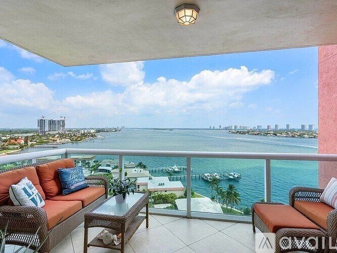 A balcony with a table and chairs overlooking a body of water.
