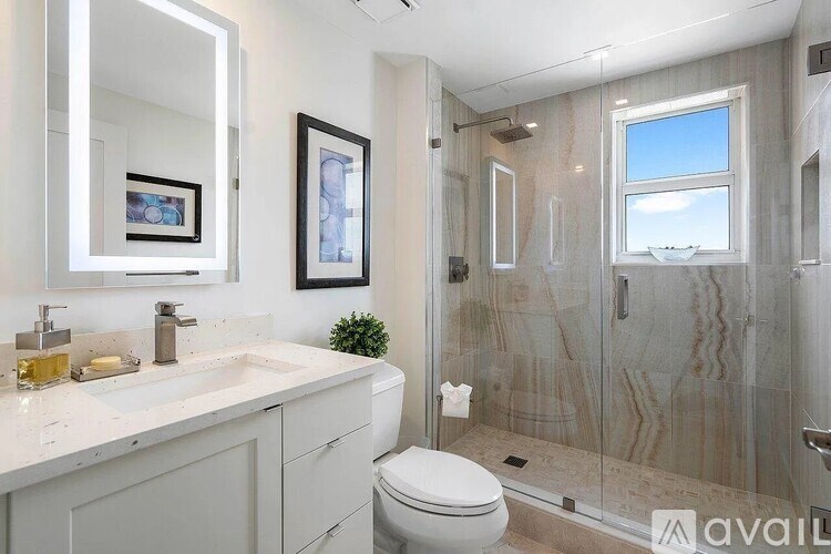 A bathroom with a toilet, sink, mirror, and shower.