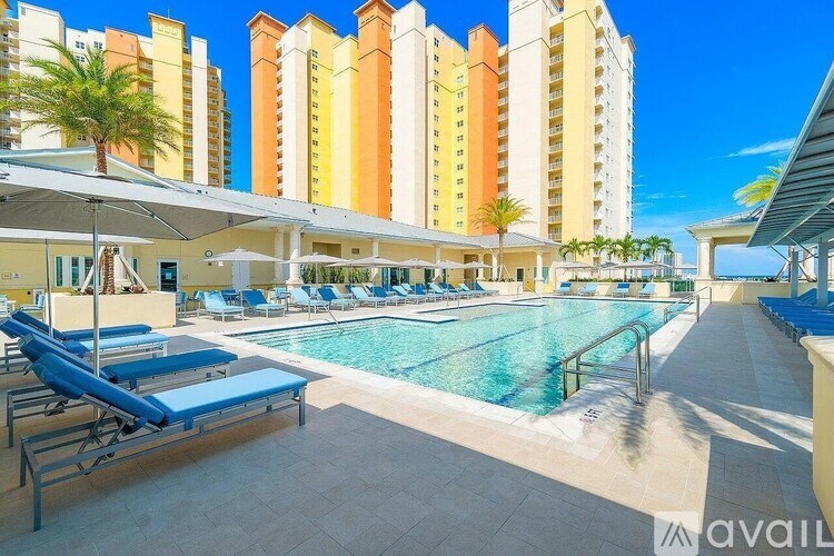 A pool area with sun loungers and a building in the background.