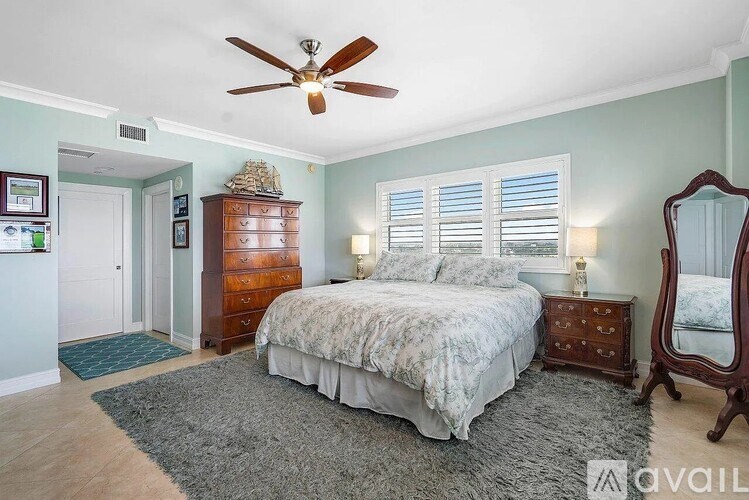 A bedroom with a large bed, a dresser, and a ceiling fan.