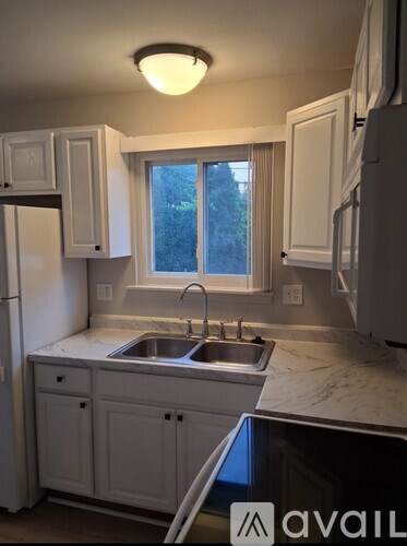 A kitchen with white cabinets and a window above the sink.