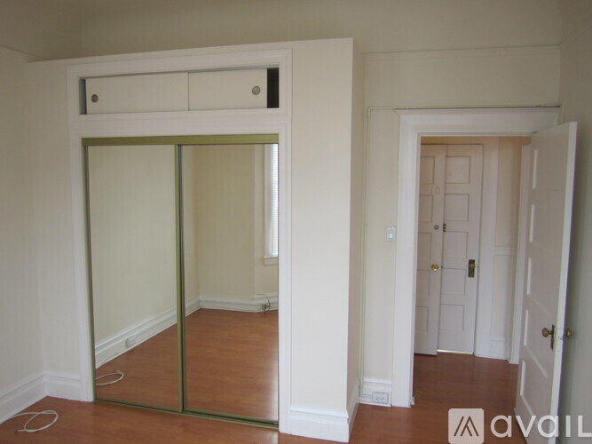 A room with a white door and a mirror on the wall.