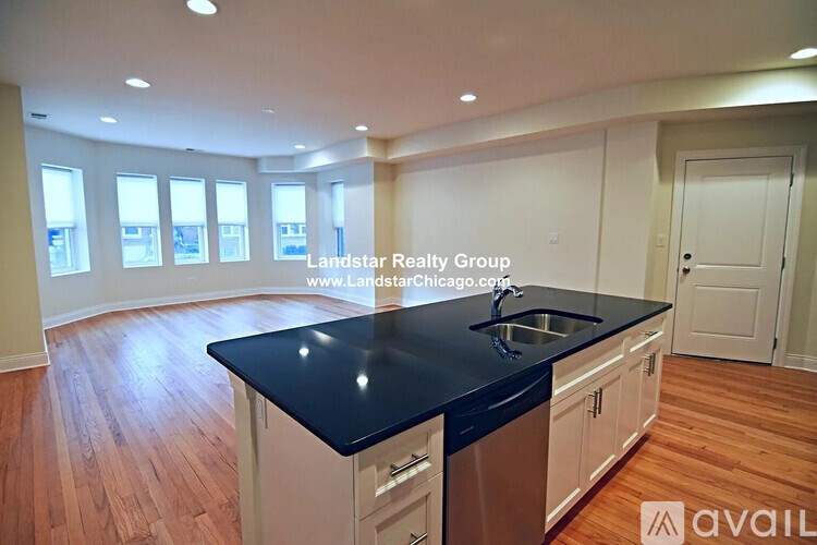 A kitchen with a black countertop and wooden flooring.