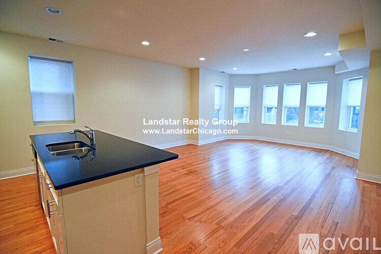 A kitchen with a black countertop and wooden flooring is available for rent.