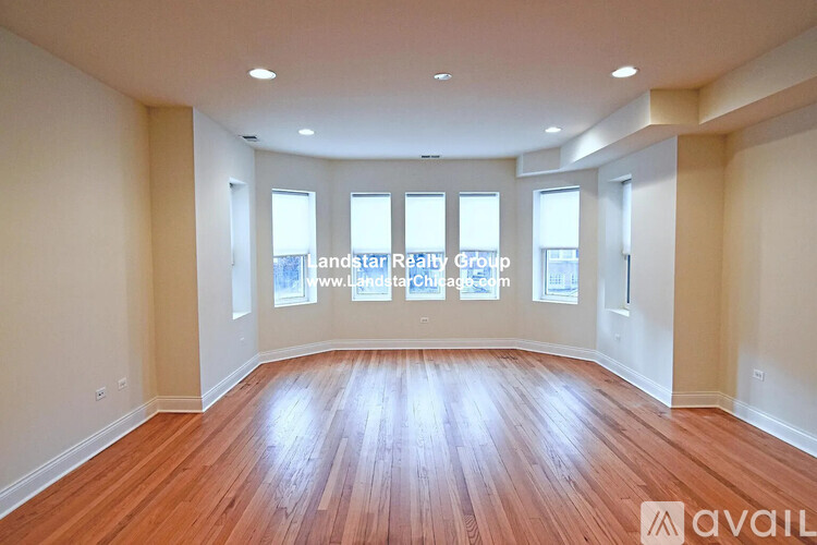 A spacious room with wooden flooring and windows.