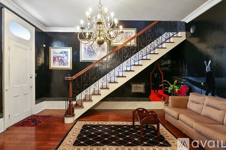 A living room with a staircase and a chandelier.