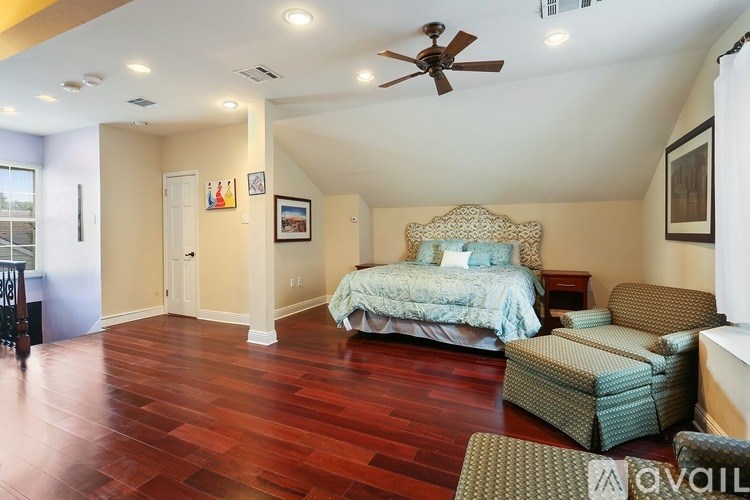 A bedroom with a bed, chair, and a ceiling fan.