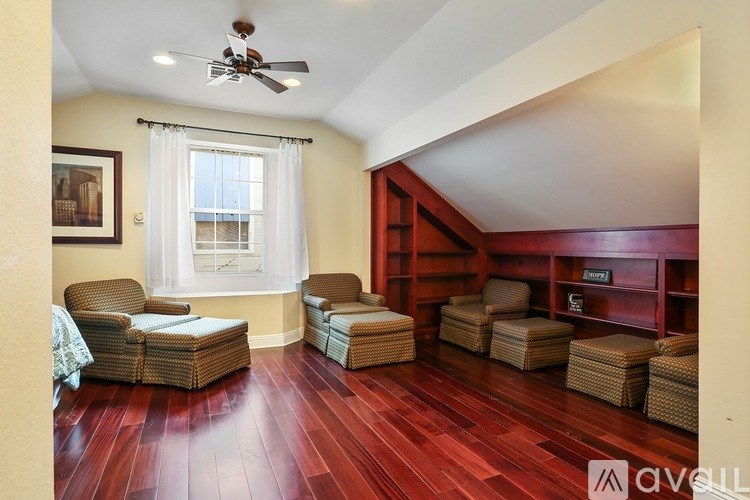 A living room with a red wooden floor and a ceiling fan.
