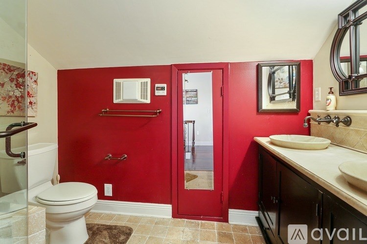 A bathroom with a red wall and a white toilet.