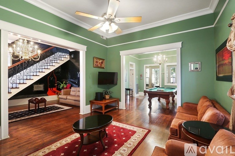 A living room with a staircase and a pool table.