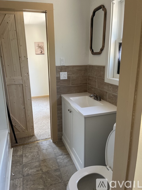 A bathroom with a toilet, sink, and mirror.