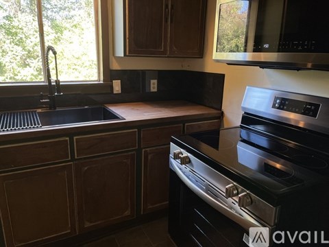 A kitchen with a black stove top oven and a black sink with a silver faucet.