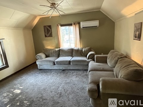 A living room with grey couches and a ceiling fan.