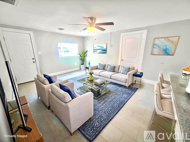 A living room with a white couch and a blue rug.