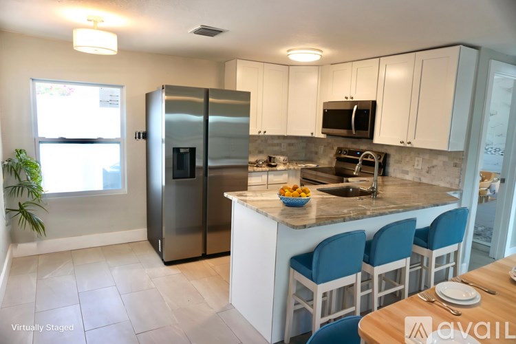 A kitchen with white cabinets and a stainless steel refrigerator.