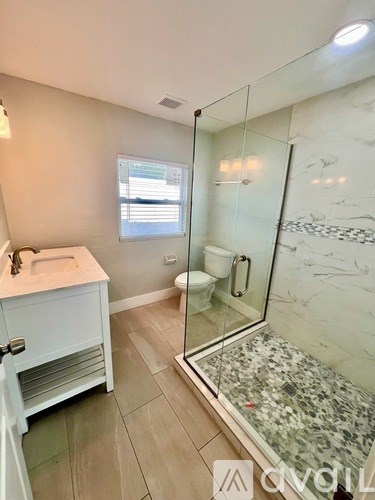 A bathroom with a walk-in shower and a white sink vanity.