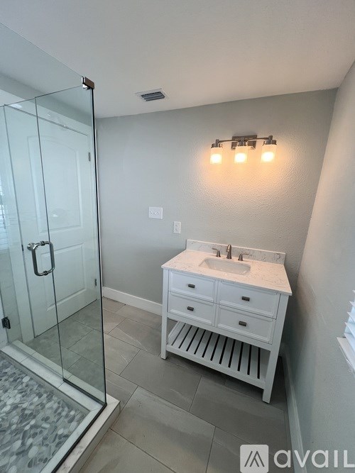 A bathroom with a sink, a shower, and a white cabinet.