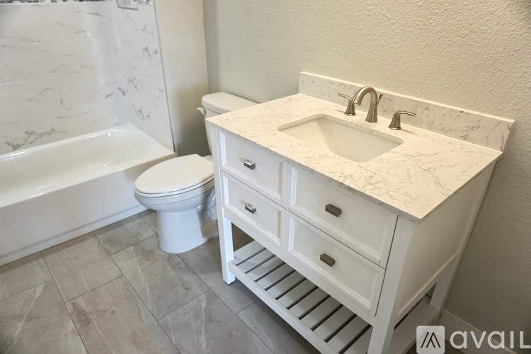 A white bathroom with a marble sink and toilet.