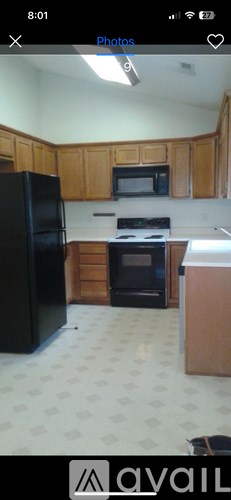 A kitchen with wooden cabinets and a black refrigerator.