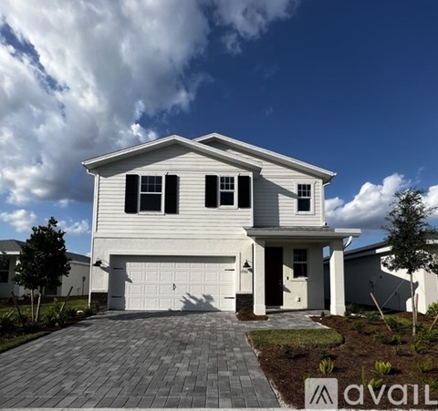 A white house with a garage door and a driveway in front.
