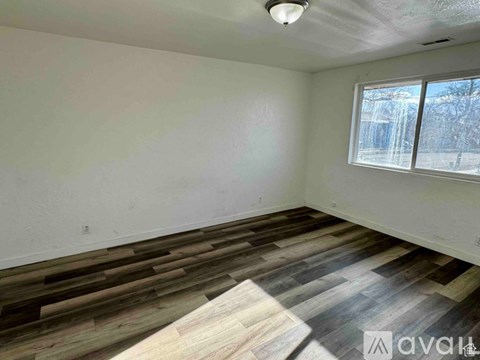 A room with wooden flooring and a window showing a snowy landscape outside.