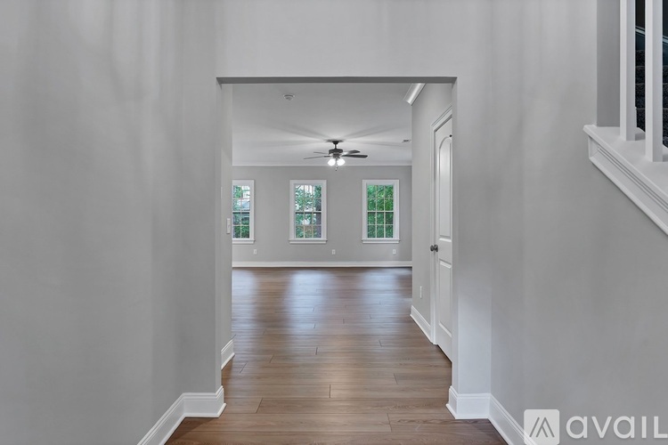 A long hallway with a fan and a door at the end.
